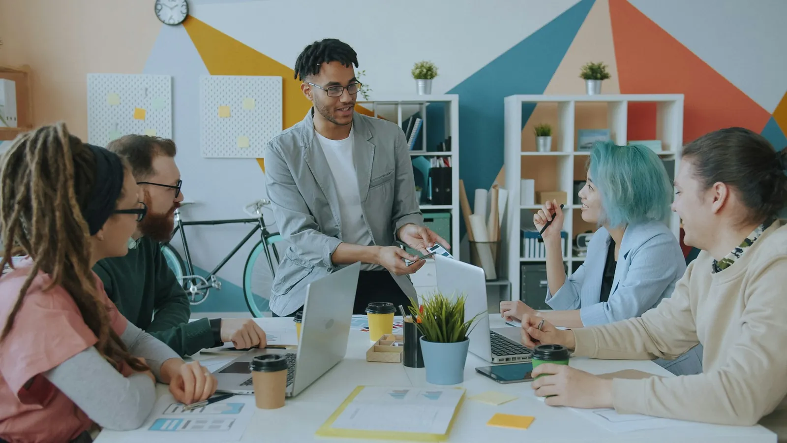 Equipe em reunião num escritório com parede de formas geométricas coloridas