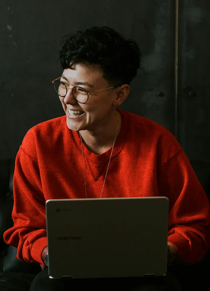 Pessoa sorrindo diante de um notebook