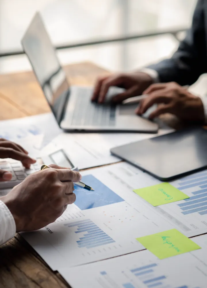 Mãos analisando relatórios e gráficos sobre uma mesa